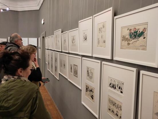 Menschen stehen vor einer langen Wand mit vielen Zeichnungen von Loriot