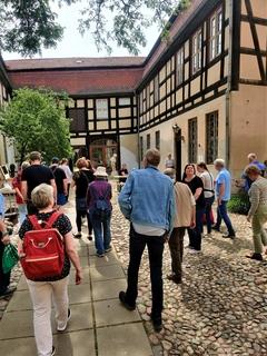 Menschen schauen sich im Hof des Museums um. Fachwerkgebäude umrahmen die Fläche