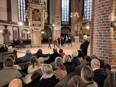 Kinder in Kostümen tanzen auf der Bühne in der St. Gotthardtkirche, daneben steht ein Mann mit Mikrofon