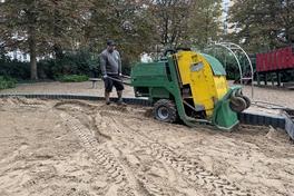 Ein Arbeiter frischt am Trauerberg den Sand auf.