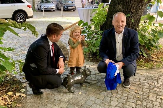 Oberbürgermeister Steffen Scheller (l.) und Thomas Krüger (Geschäftsführer der STG) enthüllen gemeinsam mit Clara, Tochter der Waldmops-Künstlerin.