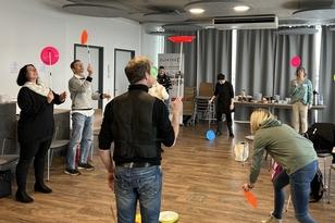 Eine Gruppe von Menschen übt das Drehen eines Plastiktellers auf einem Stab