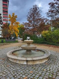 Bürgermeisterbrunnen mit wohnblöcken im Hintergrund.