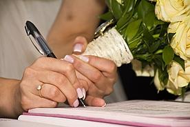 Unterschrift unter Heiratsurkunde durch Frauenhand