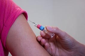 eine Impf-Spritze wird an einem Arm angesetzt