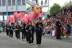 Menschen tragen ein Drachensymbol vor der Tribüne vorbei