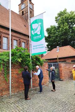 Herbert Nowotny zieht an dem Strick zum Hissen der Fahne, Birgit Patz und Steffen Scheller schauen dabei zu