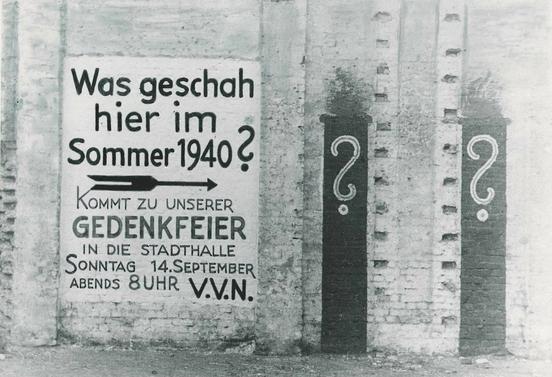 Schwarz-weiß-Aufnahme eines Posters mit dem Text: "Was geschah hier im Sommer 1940?"
