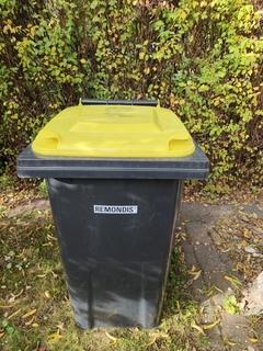 schwarze Tonne mit gelben Deckel.