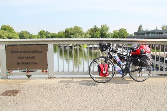 Fahrrad steht an der Jahrtausendbrücke am Geländer, im Hintergrund die Havel und das Gebäude der Werft zu sehen