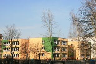 Dreistöckiges Kitagebäude mit einem Spielplatz im Vordergrund