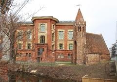 Kleine Kapelle neben einem großen Backsteinhaus.