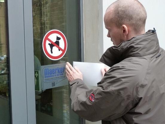 Tino Rohloff beim Anbringen eines Maerker-Aufklebers mit QR-Code am Eingang zum Altstädtischen Rathaus.