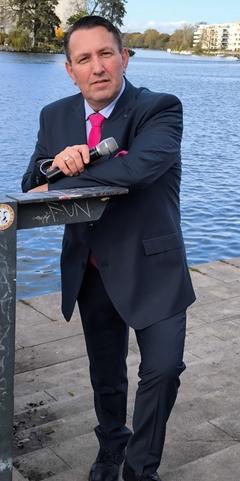 Der Sänger vor einem Wasserhintergund.