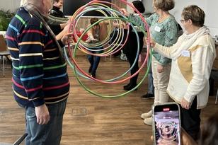 Zwei Reihen von Menschen stehen sich gegenüber und halten Hula-Hoop-Reifen in den Händen die so einen Tunnel bilden