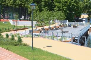 Mehrere Sitzgelegenheiten am Ufer mit Sportanlagen im Hintergrund
