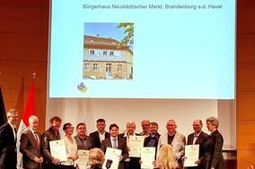 Eine Menschengruppe erhält eine Auszeichnung.