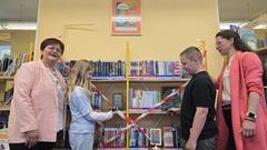Beigeordnete Alexandra Adel und Bibliothek-Direktorin Cornelia Stabrodt haben mit Schülern der Grundschule "Wilhelm Busch" das Lesesommer-Bücherregal.