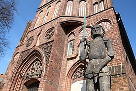 Foto von der Fassade des Rathauses und der davorstehenden Roland-Figur
