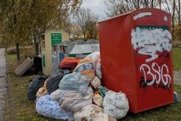 viele Altkleider liegen neben dem Altkleidercontainer