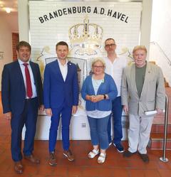 Gruppe von Personen im Rathauseinang vor dem Wappen der Stadt