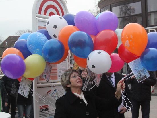 Oberbürgermeisterin Dr. Dietlind Tiemann hilft dabei, bunte Luftballons mit einer VBBr-Zeitkarte in den Himmel steigen zu lassen.