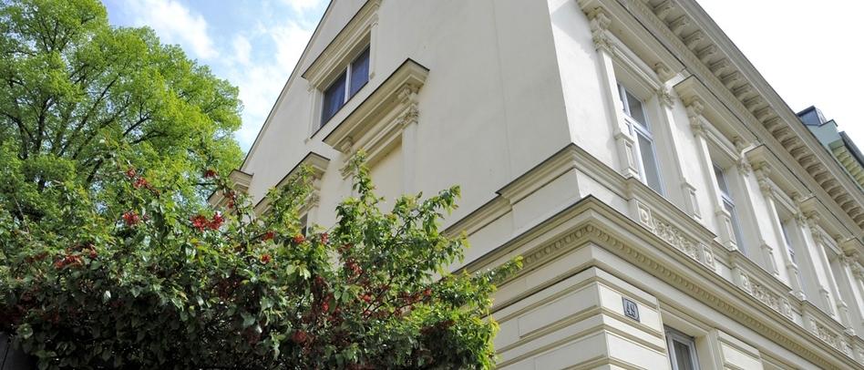 Historisches Wohnhaus mit renovierter Fassade und einem großen Baum an der Seite