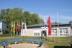 Flaggenmasten stehen auf einer Rasenfläche vor einem Gebäude.