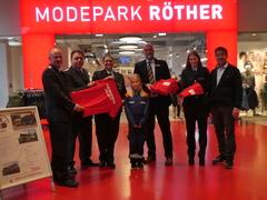 Feuerwehrleute, Filialleiter und Oberbürgermeister mit T-Shirts.