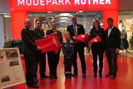 Feuerwehrleute, Filialleiter und Oberbürgermeister mit T-Shirts.