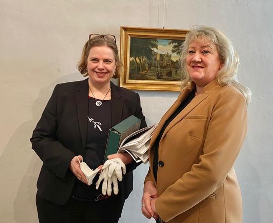 Die Leiterin des Stadtmuseums Anja Grothe und Kerstin Neitzel, Regionalleiterin der Fielmann AG, freuen sich über das Gemälde des Brandenburger Bahnhofs, das nach fast 80 Jahren „zurück nach Hause“ gekommen ist.