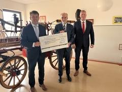 drei Personen mit einem großen Scheck in der Hand