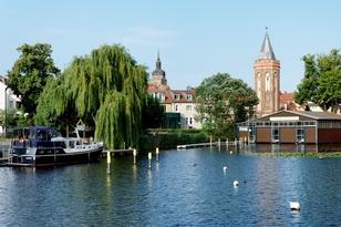 Bootsanlegestellen am Wasser mit dem Mühlentorturm und der Spitze der St. Katharinenkirche im Hintergrund
