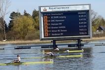 Drei Ruderboote vor der großen Anzeigentafel