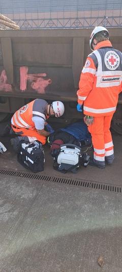 Rettungskräfte bergen eine unter einem Waggon eingeklemmte Person.