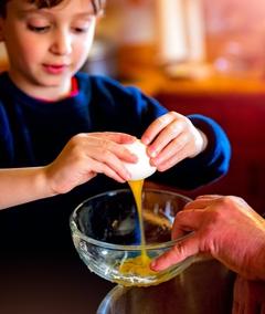 Junge, der ein rohes Ei in eine Schale tropfen lässt