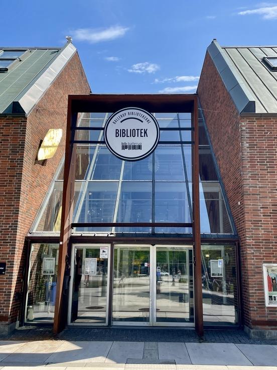 Gläserner Eingang der Bibliothek mit Backsteinmauern
