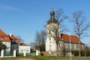 Kirchengebäude mit Kirchenturm und von Bäumen umgeben