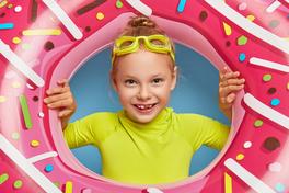 Ein Kind schaut durch einen aufgeblasenen Donut.