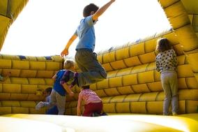 Kinder springen auf einer gelben Hüpfburg. Foto: Lukas/Pexels