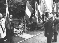 Personen die mit Fahnen an einem Grab stehen