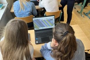 Zwei Schülerinnen schauen auf einem Laptop sich das Spiel an.