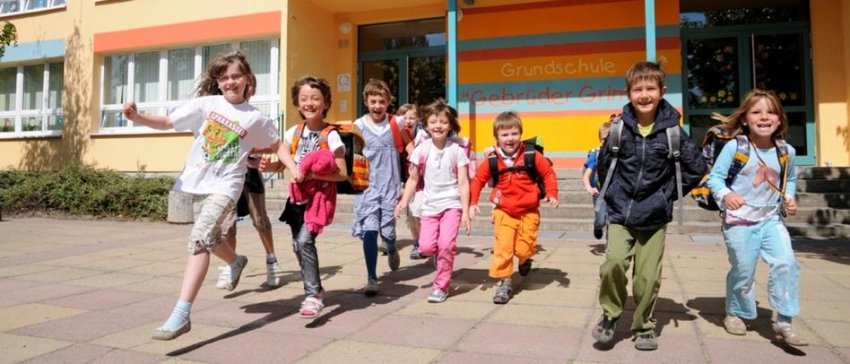 Kinder laufen lachend aus einem Schulgebäude heraus
