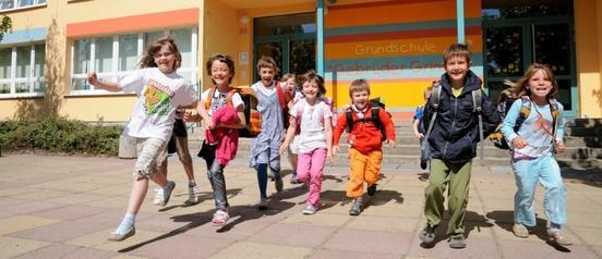 Kinder laufen lachend aus einem Schulgebäude heraus