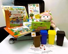 Ein Rollkoffer mit Sachbücher, Puzzle und Mini Mülltonnen für Kinder zum Thema Abfall