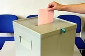 Hand wirft Stimmzettel in Wahlurne