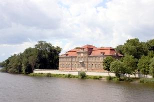 Am Wasser gelegenes Gebäude von Bäumen umgeben