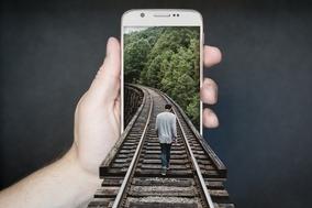 Mann läuft auf Schienen scheinbar in ein Handy rein