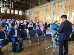 OB Steffen Scheller am Rednerpult vor dem auf Stühlen sitzenden Publikum des Symposiums