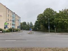 Straßenkreuzung und am Rand ein Wohnblock der Gerostr. 63 sowie gegenüber Bäume des Parks am Walter-Rathenau-Platz